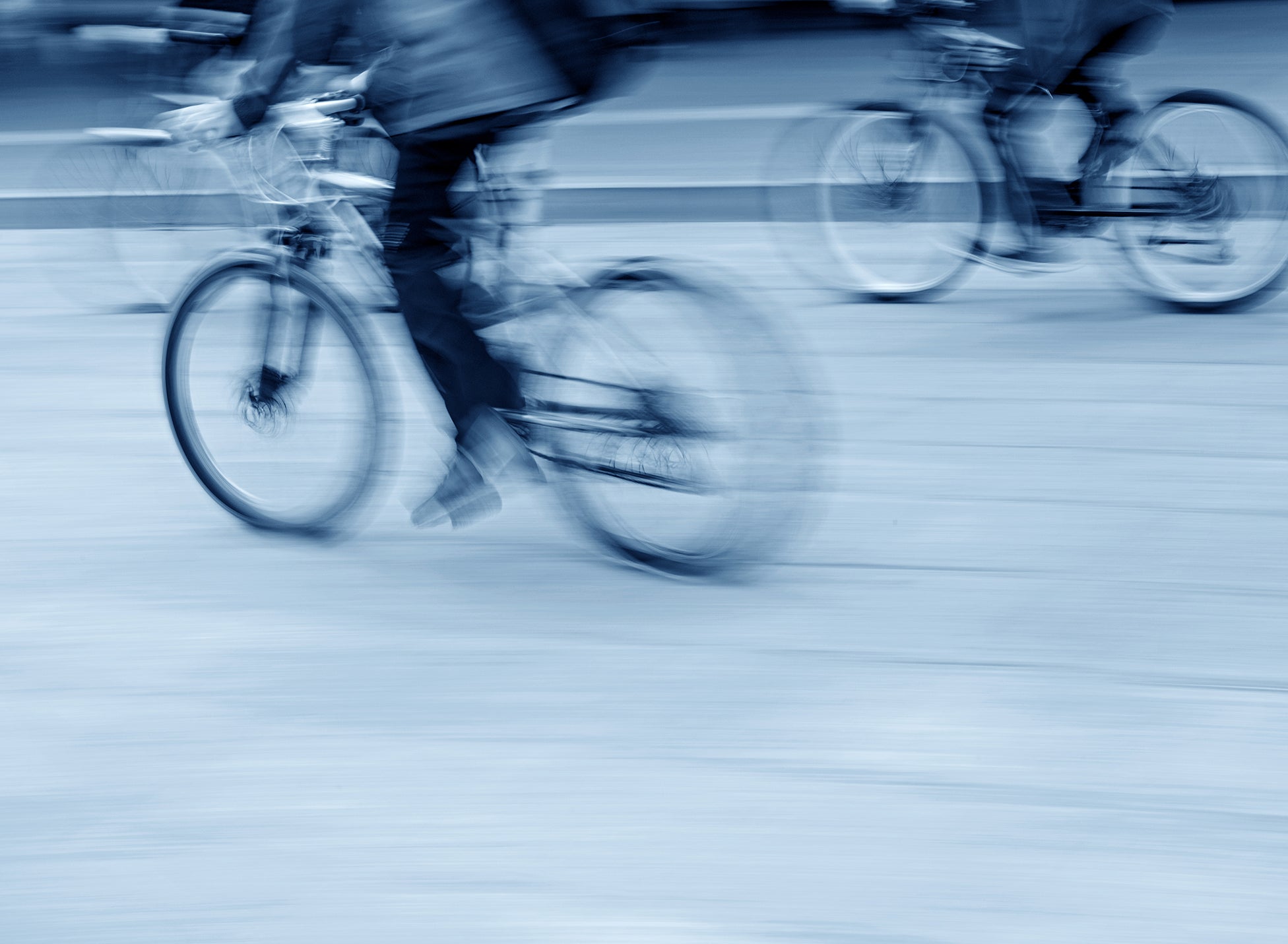 Blurred cyclescheme image of two peole riding bikes in a town
